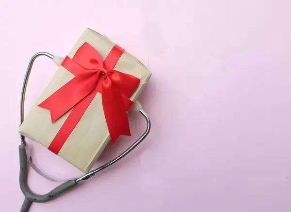 medical stethoscope with gift box isolated on a pink pastel background. concept christmas and new year.horizontal photo