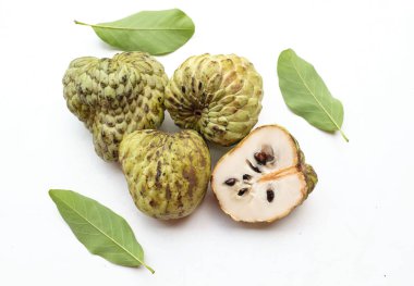 Taze yeşil kremalı elma, elma şekeri, anona cherimola (annona squamosa l.) beyaz arka planda yalıtılmış yapraklarla ikiye bölünmüş meyve. Tropikal egzotik meyve ve sağlıklı meyve