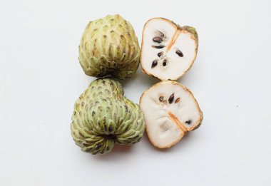 Taze yeşil kremalı elma, elma şekeri, anona cherimola (annona squamosa l.) beyaz arka planda yalıtılmış yapraklarla ikiye bölünmüş meyve. Tropikal egzotik meyve ve sağlıklı meyve