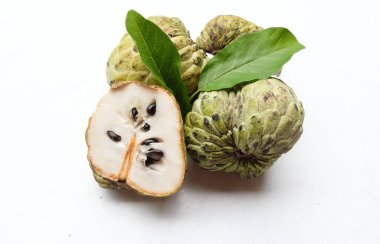 Taze yeşil kremalı elma, elma şekeri, anona cherimola (annona squamosa l.) beyaz arka planda yalıtılmış yapraklarla ikiye bölünmüş meyve. Tropikal egzotik meyve ve sağlıklı meyve