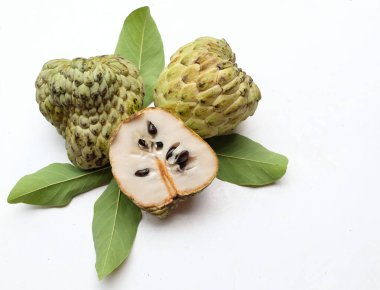 Taze yeşil kremalı elma, elma şekeri, anona cherimola (annona squamosa l.) beyaz arka planda yalıtılmış yapraklarla ikiye bölünmüş meyve. Tropikal egzotik meyve ve sağlıklı meyve