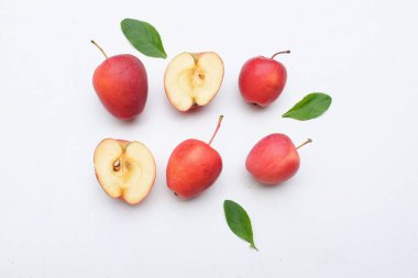 Taze organik olgunlaşmış kırmızı cüce elma, prenses elması, mini elma, küçük elma, kiraz elması, tam kırmızı elma, yarım dilim yeşil yapraklı beyaz arka plan