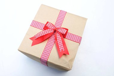   Beyaz arka planda kırmızı kurdeleli el işi kağıt hediye kutusu. Yeni yıl, Noel, Sevgililer Günü konsepti.