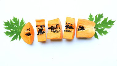 Üst ve düz bir zemin üzerinde yeşil yapraklı, dilimlenmiş, olgun bir papaya meyvesi papaya uzanır. Sağlıklı beslenme için sebze ve meyve.
