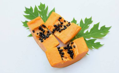 Üst ve düz bir zemin üzerinde yeşil yapraklı, dilimlenmiş, olgun bir papaya meyvesi papaya uzanır. Sağlıklı beslenme için sebze ve meyve.