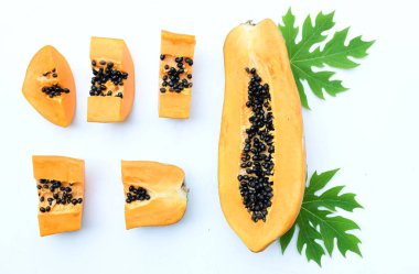 Üst ve düz bir zemin üzerinde yeşil yapraklı, dilimlenmiş, olgun bir papaya meyveli papaya uzanır. Sağlıklı beslenme için sebze ve meyve.