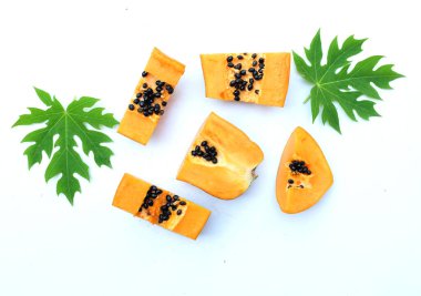 Üst ve düz bir zemin üzerinde yeşil yapraklı, dilimlenmiş, olgun bir papaya meyveli papaya uzanır. Sağlıklı beslenme için sebze ve meyve.