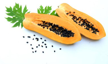 Üst ve düz bir zemin üzerinde yeşil yapraklı, dilimlenmiş, olgun bir papaya meyveli papaya uzanır. Sağlıklı beslenme için sebze ve meyve.