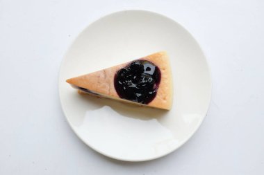 Üst ve düz bir porsiyon yaban mersinli kek beyaz bir plaka üzerinde mor yaban mersinli süsleme beyaz zemin üzerinde izole