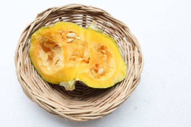 Bir yığın taze çiğ Japon balkabağı (Cucurbita moschata), Kabocha kabağı, beyaz bir arka planda izole edilmiş bir hasır sepet içinde. Sağlıklı gıda sebze, meyve ve gıda ticareti fikri