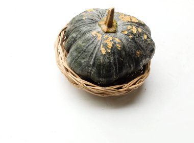 Bir yığın taze çiğ Japon balkabağı (Cucurbita moschata), Kabocha kabağı, beyaz bir arka planda izole edilmiş bir hasır sepet içinde. Sağlıklı gıda sebze, meyve ve gıda ticareti fikri