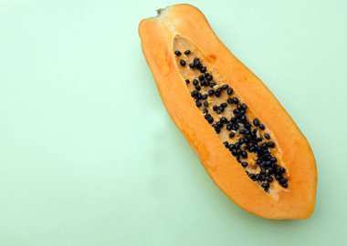 Üst ve düz bir zemin üzerinde yeşil bir zemin üzerine izole edilmiş dilimlenmiş, olgun papaya meyveli papaya uzanır. Sağlıklı beslenme için sebze ve meyve.