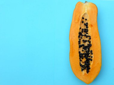 Üst ve düz bir zemin üzerinde tatlı olgun papaya meyveli papaya ve dilimlenmiş mavi bir zemin uzanıyor. Sağlıklı beslenme için sebze ve meyve.