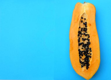 Üst ve düz bir zemin üzerinde tatlı olgun papaya meyveli papaya ve dilimlenmiş mavi bir zemin uzanıyor. Sağlıklı beslenme için sebze ve meyve.