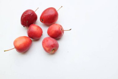 Bir grup taze organik kırmızı cüce elma, prenses elması, mini elma, küçük elma, kiraz elması, yeşil yapraklı parlak kırmızı elmalar beyaz arka planda izole edilmiş. sağlıklı meyve kavramı