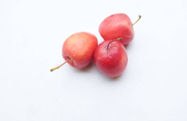 Bir grup taze organik kırmızı cüce elma, prenses elması, mini elma, küçük elma, kiraz elması, yeşil yapraklı parlak kırmızı elmalar beyaz arka planda izole edilmiş. sağlıklı meyve kavramı