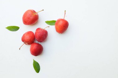 Bir grup taze organik kırmızı cüce elma, prenses elması, mini elma, küçük elma, kiraz elması, yeşil yapraklı parlak kırmızı elmalar beyaz arka planda izole edilmiş. sağlıklı meyve kavramı