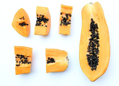 Üst ve düz bir zemin üzerinde yeşil yapraklı, dilimlenmiş, olgun bir papaya meyveli papaya uzanır. Sağlıklı beslenme için sebze ve meyve.