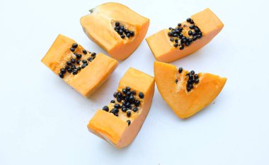 Üst ve düz bir zemin üzerinde yeşil yapraklı, dilimlenmiş, olgun bir papaya meyveli papaya uzanır. Sağlıklı beslenme için sebze ve meyve.