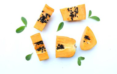 Üst ve düz bir zemin üzerinde yeşil yapraklı, dilimlenmiş, olgun bir papaya meyveli papaya uzanır. Sağlıklı beslenme için sebze ve meyve.