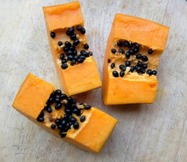 Üst ve düz, olgun papaya meyveli papaya, ahşap masada dilimlenmiş. Sağlıklı beslenme için sebze ve meyve.