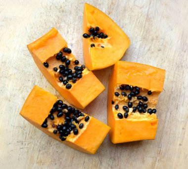 Üst ve düz, olgun papaya meyveli papaya, ahşap masada dilimlenmiş. Sağlıklı beslenme için sebze ve meyve.