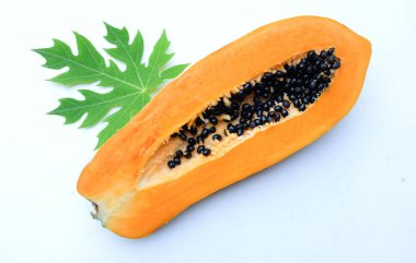 Üst ve düz bir zemin üzerinde yeşil yapraklı, dilimlenmiş, olgun bir papaya meyveli papaya uzanır. Sağlıklı beslenme için sebze ve meyve.