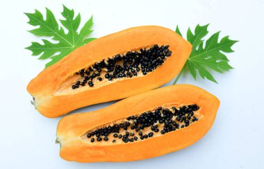Üst ve düz bir zemin üzerinde yeşil yapraklı, dilimlenmiş, olgun bir papaya meyveli papaya uzanır. Sağlıklı beslenme için sebze ve meyve.