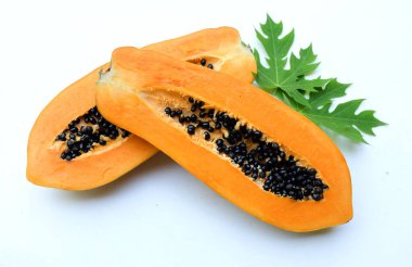 Üst ve düz bir zemin üzerinde yeşil yapraklı, dilimlenmiş, olgun bir papaya meyveli papaya uzanır. Sağlıklı beslenme için sebze ve meyve.