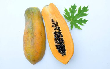 Üst ve düz bir zemin üzerinde yeşil yapraklı, dilimlenmiş, olgun bir papaya meyveli papaya uzanır. Sağlıklı beslenme için sebze ve meyve.