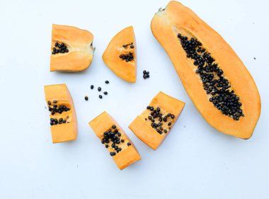 Üst ve düz bir zemin üzerinde yeşil yapraklı, dilimlenmiş, olgun bir papaya meyveli papaya uzanır. Sağlıklı beslenme için sebze ve meyve.