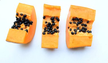 Üst ve düz bir zemin üzerinde yeşil yapraklı, dilimlenmiş, olgun bir papaya meyveli papaya uzanır. Sağlıklı beslenme için sebze ve meyve.