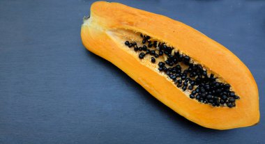 Üst ve düz bir zemin üzerinde yeşil yapraklı, dilimlenmiş, olgun bir papaya meyvesi papaya uzanır. Sağlıklı beslenme için sebze ve meyve.
