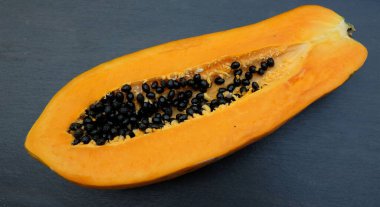 Üst ve düz bir zemin üzerinde yeşil yapraklı, dilimlenmiş, olgun bir papaya meyvesi papaya uzanır. Sağlıklı beslenme için sebze ve meyve.