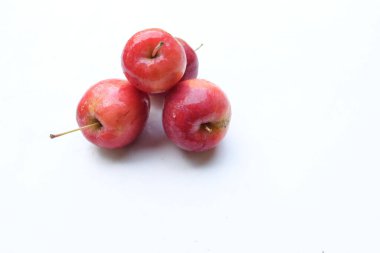 Bir grup taze organik kırmızı cüce elma, prenses elması, mini elma, küçük elma, kiraz elması, yeşil yapraklı parlak kırmızı elmalar beyaz arka planda izole edilmiş. sağlıklı meyve kavramı