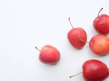 Fotokopi uzayı taze bir organik kırmızı cüce elması, prenses elması, mini elma, küçük elma, kiraz elması, yeşil yapraklı parlak kırmızı elmalar beyaz arka planda izole edilmiş. sağlıklı meyve kavramı