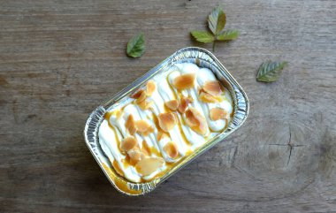 Karamelli badem soslu taze süt pastası nefis görünüyor. Ahşap bir masa arkaplanında izole edilmiş.