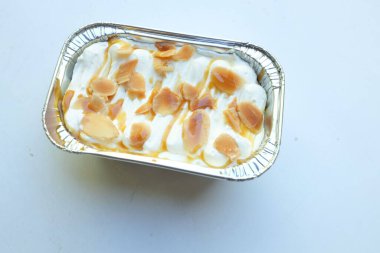 Karamelli badem soslu taze süt pastası nefis görünüyor. Beyaz bir arka planda izole edilmiş.