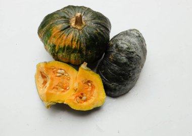 Bir yığın taze çiğ Japon balkabağı (Cucurbita moschata), Kabocha kabağı, hem top ve kesim, beyaz bir sırt üzerinde sarı et izole göstermektedir. Sağlıklı gıda sebze, meyve ve gıda işi 