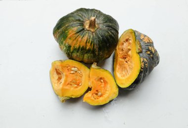 Bir yığın taze çiğ Japon balkabağı (Cucurbita moschata), Kabocha kabağı, hem top ve kesim, beyaz bir sırt üzerinde sarı et izole göstermektedir. Sağlıklı gıda sebze, meyve ve gıda işi 