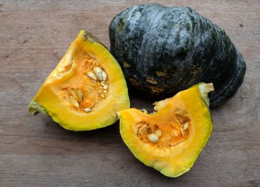 Bir yığın taze çiğ Japon balkabağı (Cucurbita moschata), Kabocha kabağı, hem top ve kesim, ahşap bir masa üzerinde sarı et izole gösterir. Sağlıklı gıda sebze, meyve ve gıda iş 
