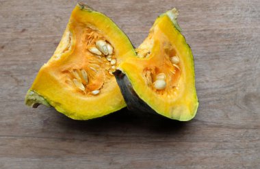 Bir yığın taze çiğ Japon balkabağı (Cucurbita moschata), Kabocha kabağı, hem top ve kesim, ahşap bir masa üzerinde sarı et izole gösterir. Sağlıklı gıda sebze, meyve ve gıda iş 