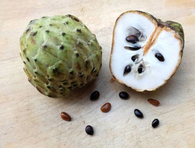 Taze yeşil kremalı elma, elma şekeri, anona cherimola (annona squamosa l.) beyaz arka planda yalıtılmış yapraklarla ikiye bölünmüş meyve. Tropikal egzotik meyve ve sağlıklı meyve