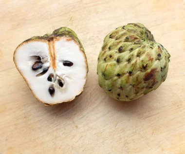 Taze yeşil kremalı elma, elma şekeri, anona cherimola (annona squamosa l.) beyaz arka planda yalıtılmış yapraklarla ikiye bölünmüş meyve. Tropikal egzotik meyve ve sağlıklı meyve