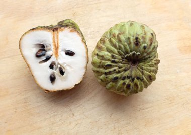 Taze yeşil kremalı elma, elma şekeri, anona cherimola (annona squamosa l.) beyaz arka planda yalıtılmış yapraklarla ikiye bölünmüş meyve. Tropikal egzotik meyve ve sağlıklı meyve