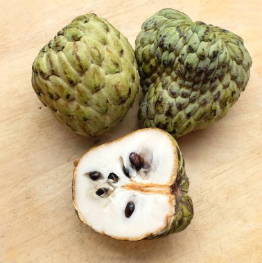 Taze yeşil kremalı elma, elma şekeri, anona cherimola (annona squamosa l.) beyaz arka planda yalıtılmış yapraklarla ikiye bölünmüş meyve. Tropikal egzotik meyve ve sağlıklı meyve