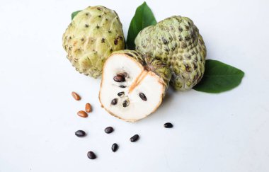 Taze yeşil kremalı elma, elma şekeri, anona cherimola (annona squamosa l.) beyaz arka planda yalıtılmış yapraklarla ikiye bölünmüş meyve. Tropikal egzotik meyve ve sağlıklı meyve