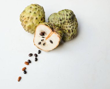 Taze yeşil kremalı elma, elma şekeri, anona cherimola (annona squamosa l.) beyaz arka planda yalıtılmış yapraklarla ikiye bölünmüş meyve. Tropikal egzotik meyve ve sağlıklı meyve