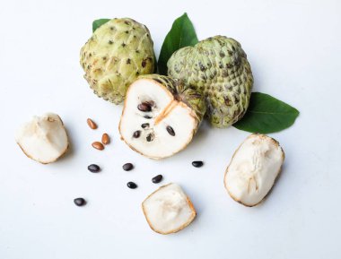 Taze yeşil kremalı elma, elma şekeri, anona cherimola (annona squamosa l.) beyaz arka planda yalıtılmış yapraklarla ikiye bölünmüş meyve. Tropikal egzotik meyve ve sağlıklı meyve