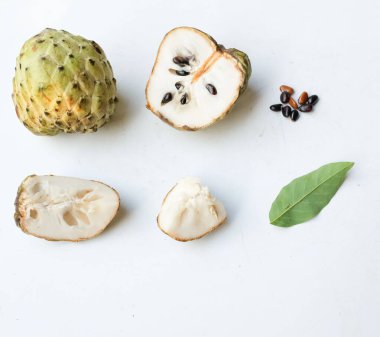 Taze yeşil kremalı elma, elma şekeri, anona cherimola (annona squamosa l.) beyaz arka planda yalıtılmış yapraklarla ikiye bölünmüş meyve. Tropikal egzotik meyve ve sağlıklı meyve